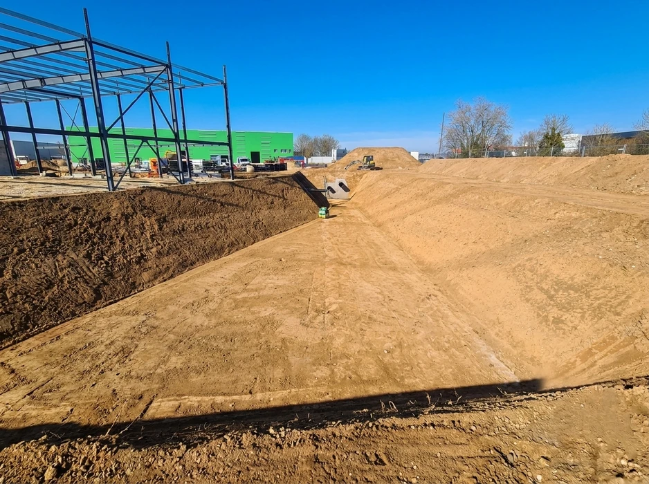 Chantier de construction en extérieur avec tranchée creusée dans terre argileuse orange