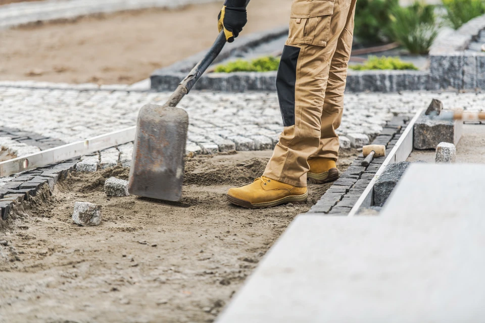 Scène extérieure de chantier avec ouvrier utilisant un outil pneumatique pour découpe de matériau dur